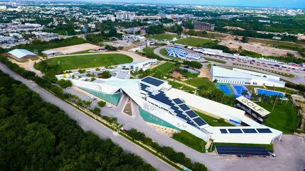 MACC ACADEMY — aerial view of the completed campus, sports fields and solar rooftops surrounded by the Cancún cityscape