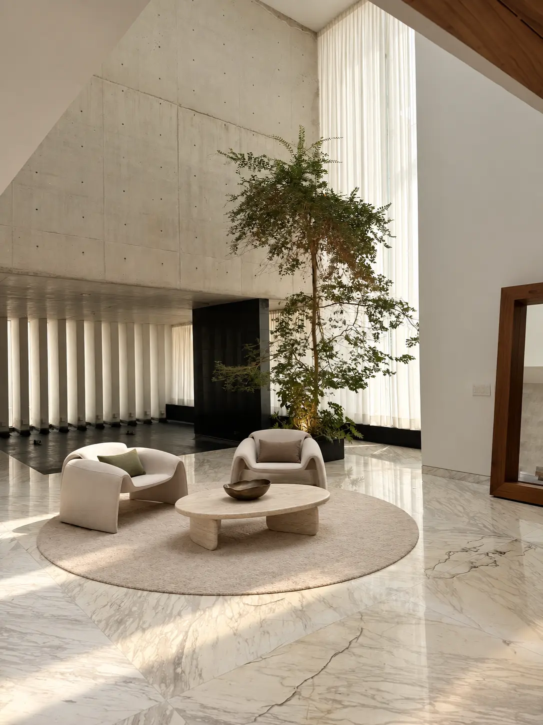 Double height hall of Cedros House with exposed concrete wall, indoor tree and marble flooring